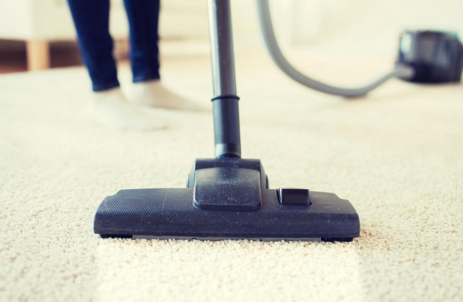 Vacuum cleaner head moving across a light-coloured carpet in a UAE apartment